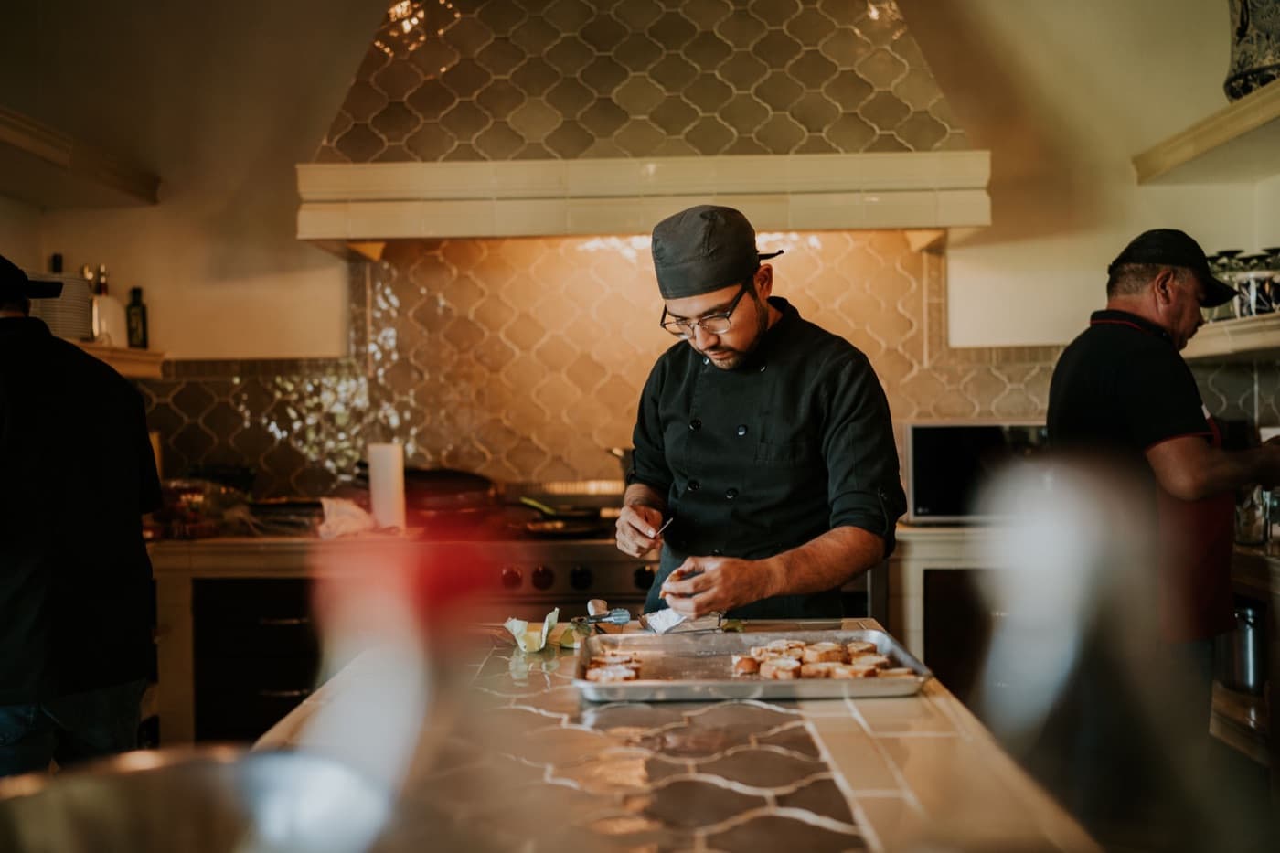 A chef plating dishes at a restaurant kitchen pass